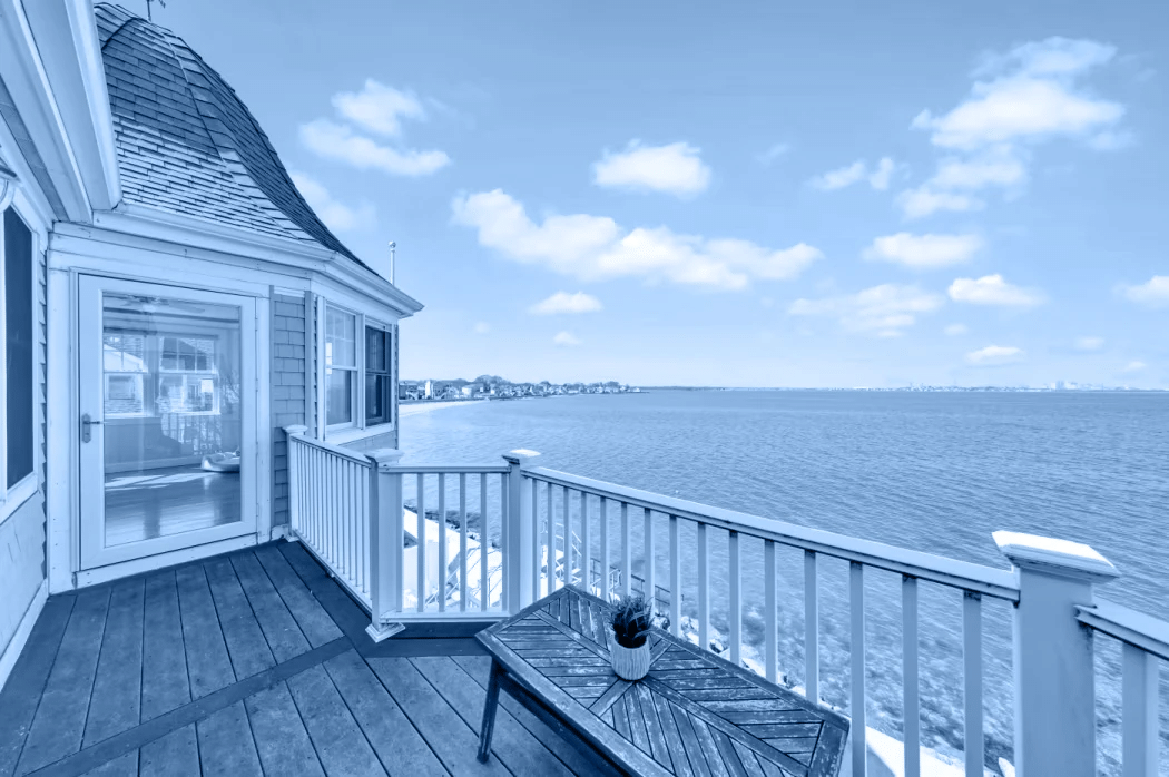 A waterfront home and deck overlooking the bay, with the SPPI blue photo tint.